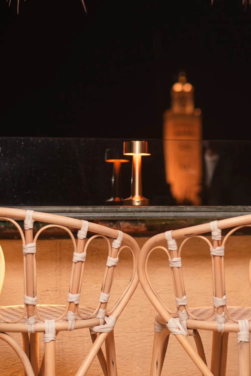 Chaises en cannage et lampe dorée, la Koutoubia illuminée la nuit