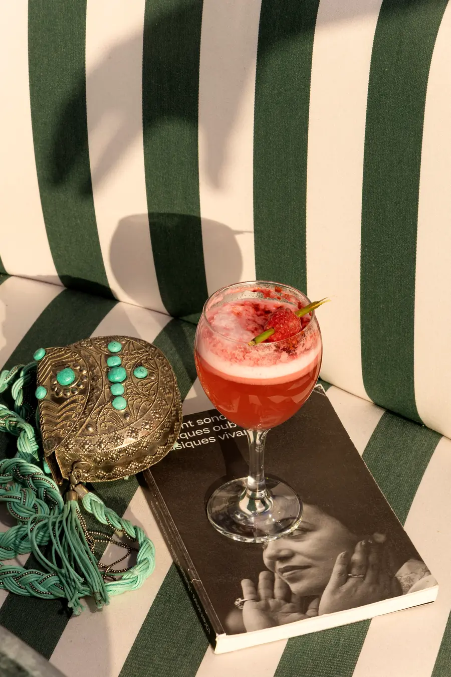 Cocktail rose posé sur la banquette rayée de SAMA